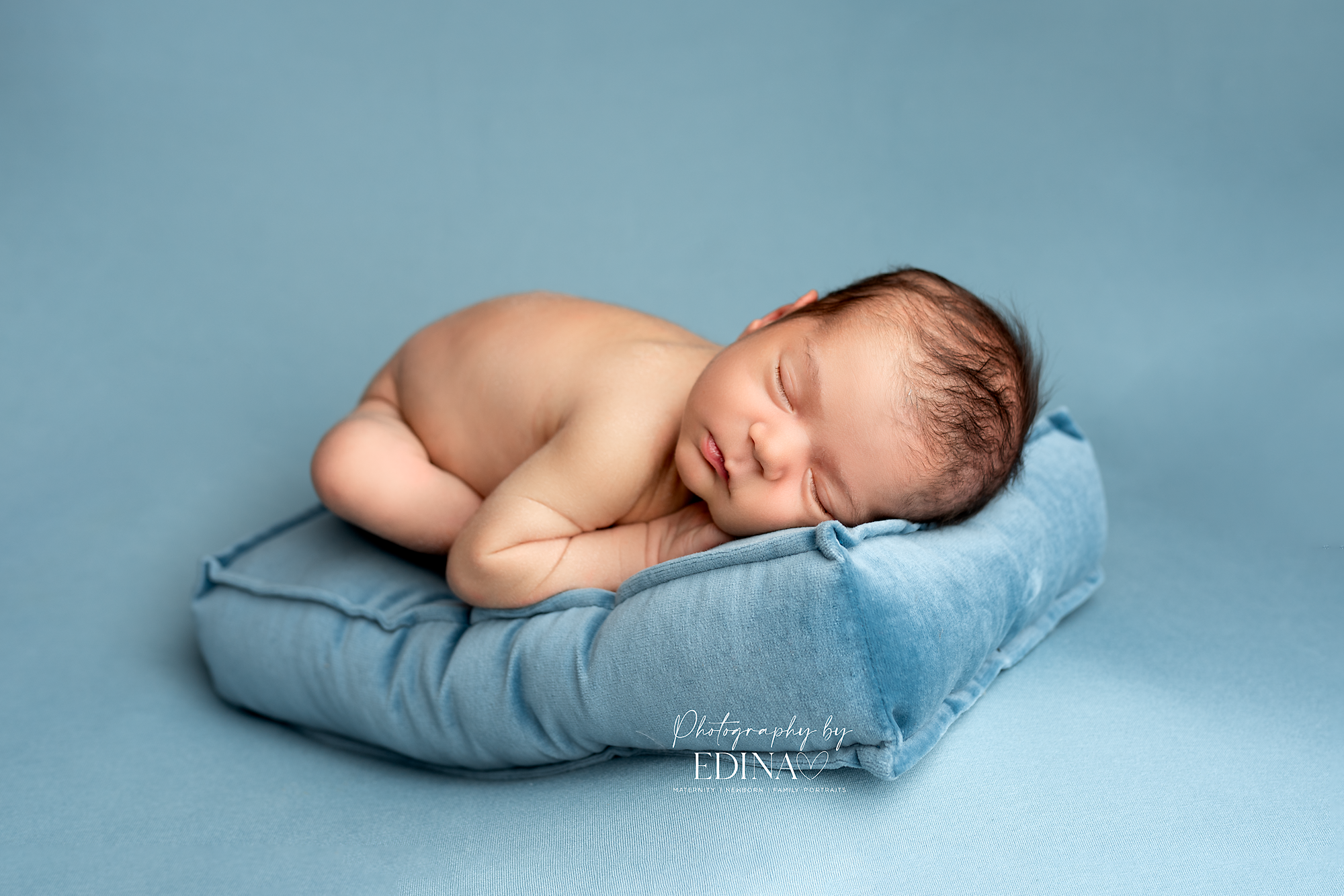 baby boy laid on blue mattress