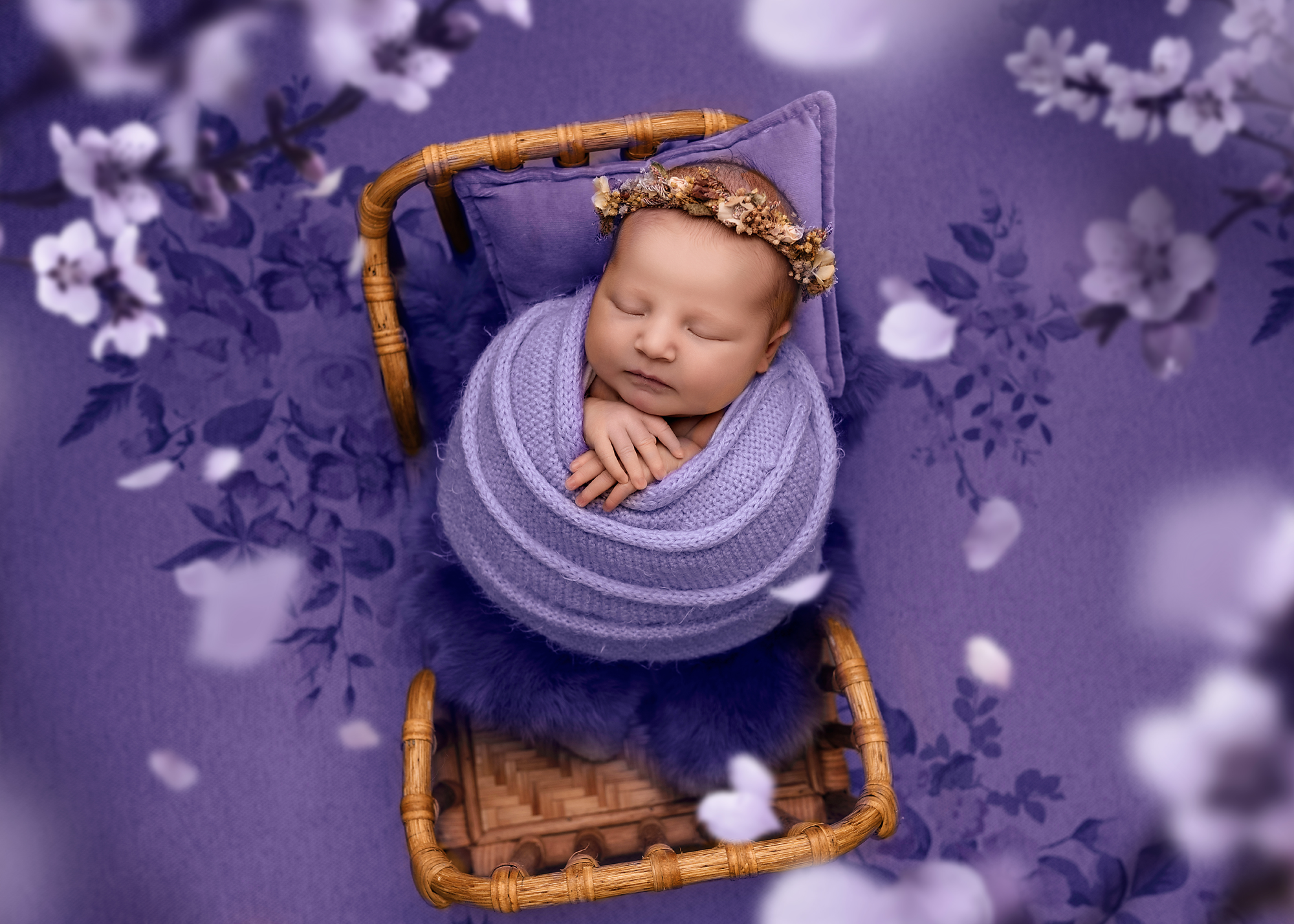 newborn baby wrapped in purple knitted wrap with flowers